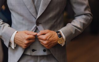man in gray suit jacket wearing gold and white analog watch