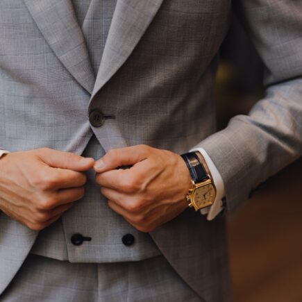 man in gray suit jacket wearing gold and white analog watch