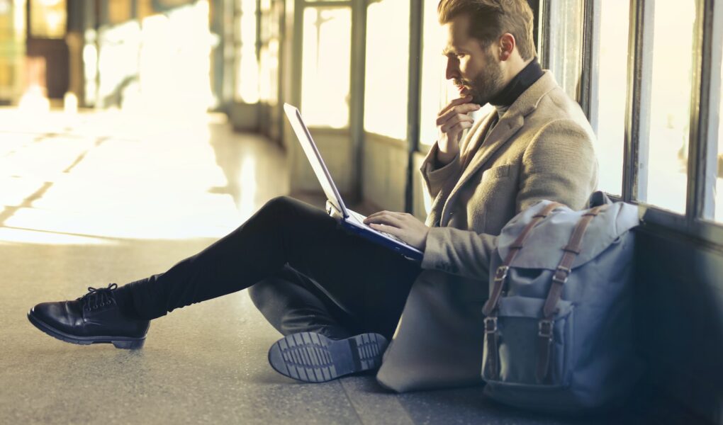 man sitting on floor while using laptop